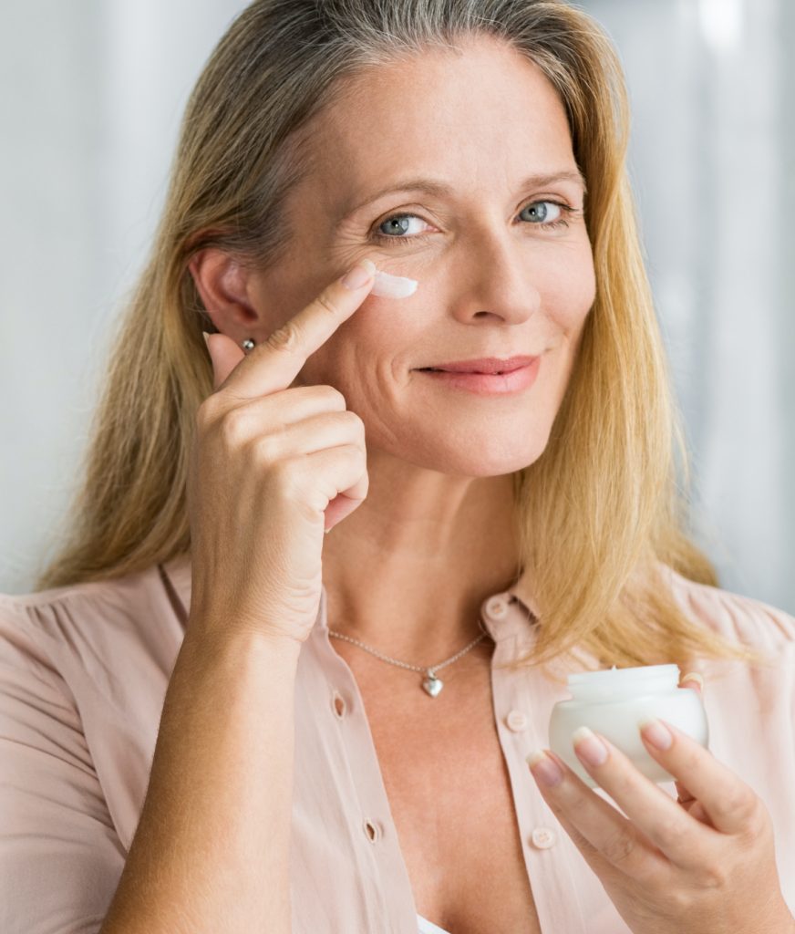 Woman applying cream to aging skin