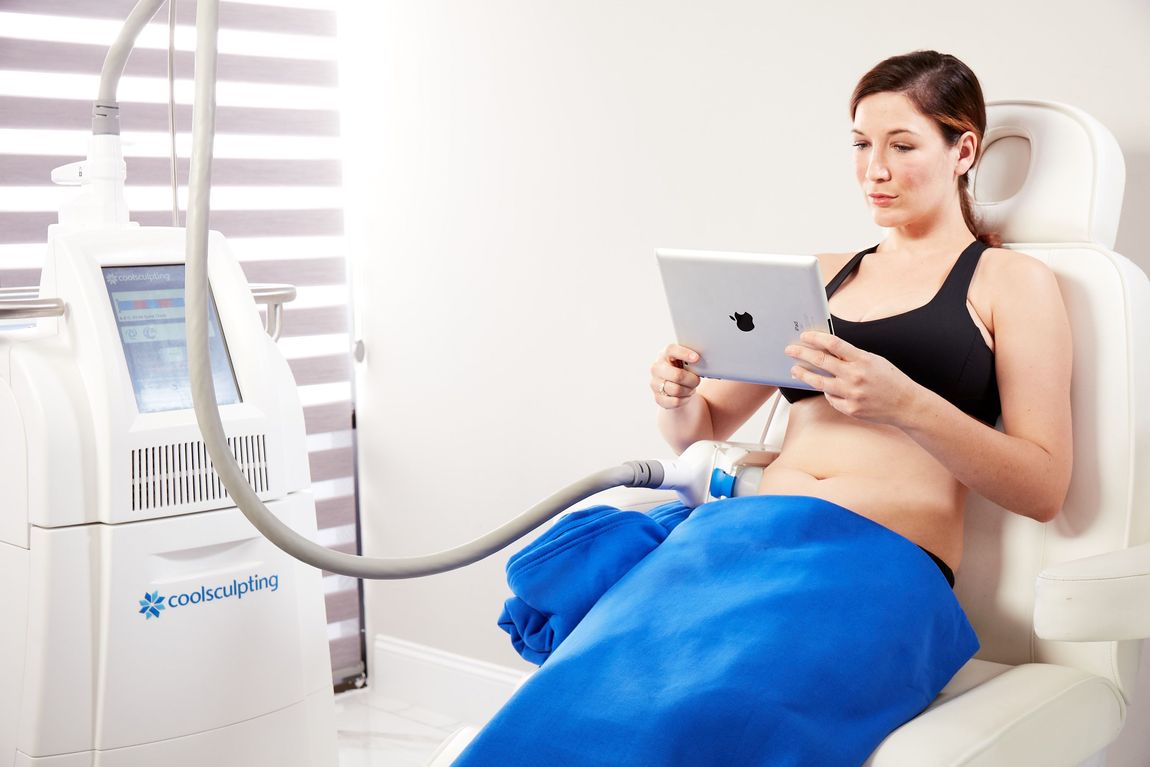 Woman getting a CoolSculpting<sup>®</sup> as she uses an iPad